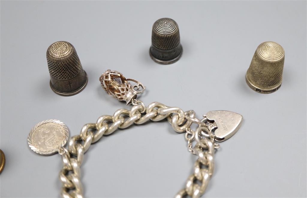 A silver charm bracelet hung with four assorted charms and four thimbles including two silver.